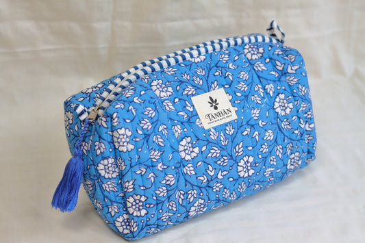 Blue floral-patterned cosmetic bag with a white label on a light background
